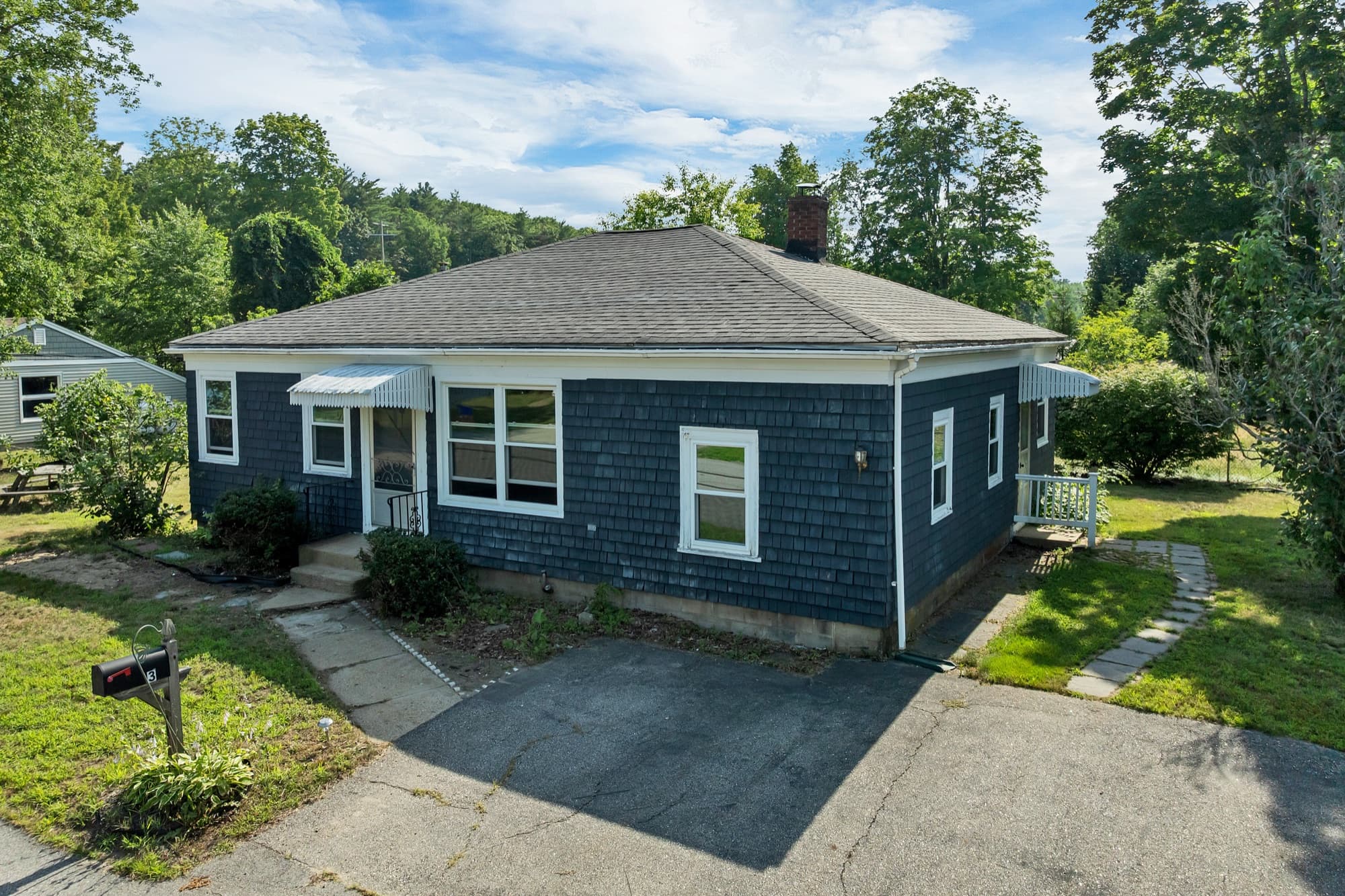 Front exterior of the slate blue shingled ranch at 3 Pond Street, with a paved driveway